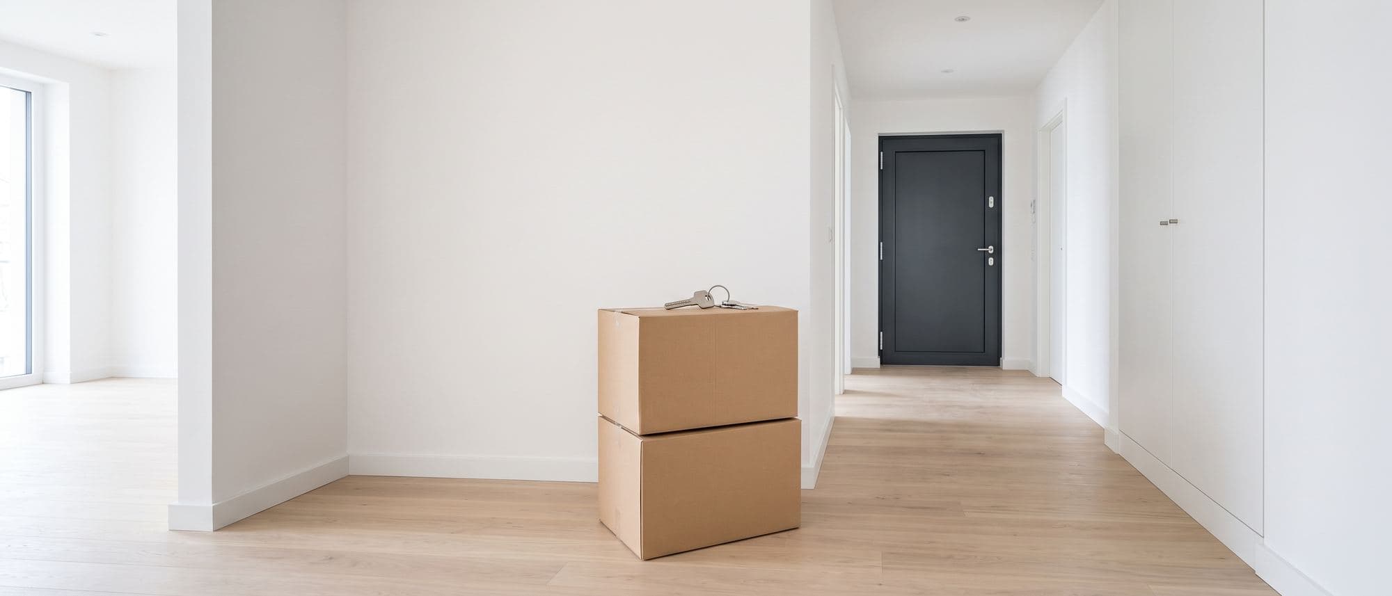 Entrée d’un logement récent en cours d’emménagement, cartons fermés et trousseau de clés neuves posé dessus
