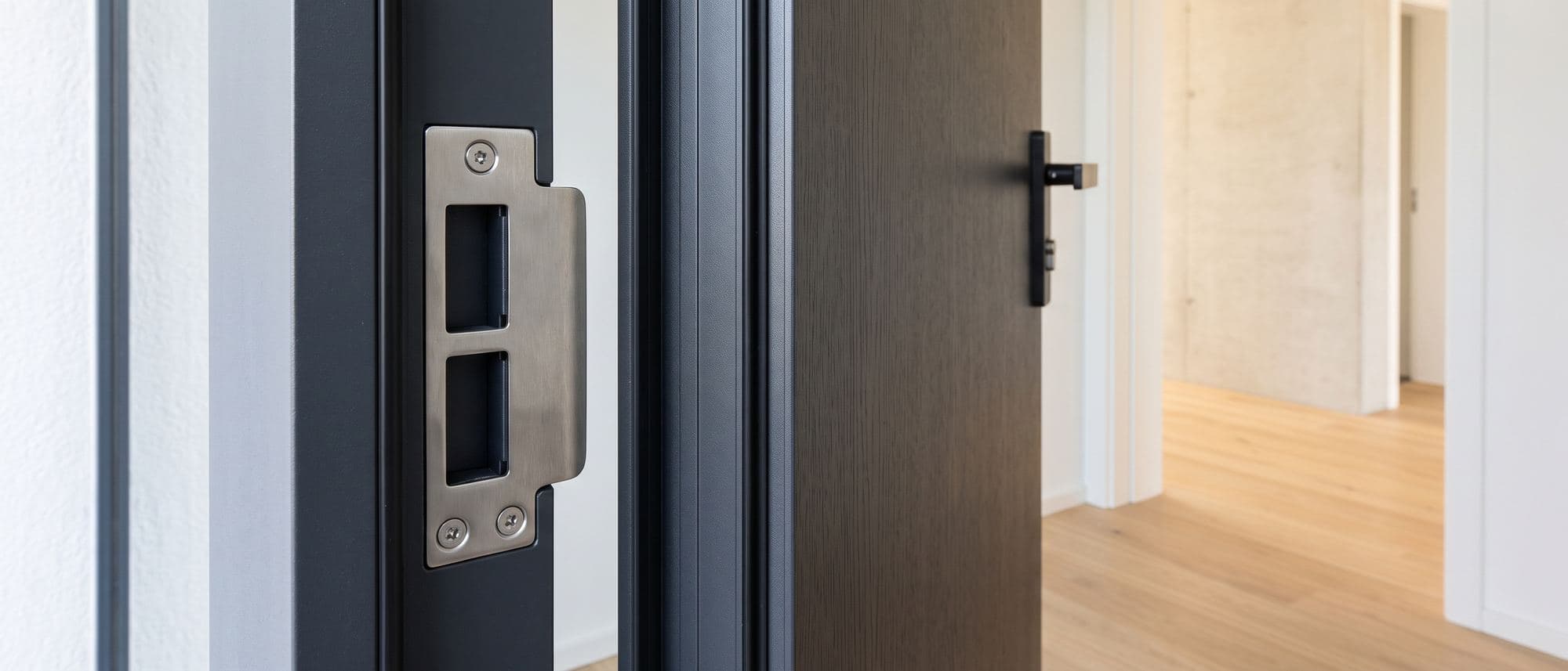 Dormant d’une porte d’entrée contemporaine équipé d’une gâche renforcée en inox neuve, porte entrebâillée
